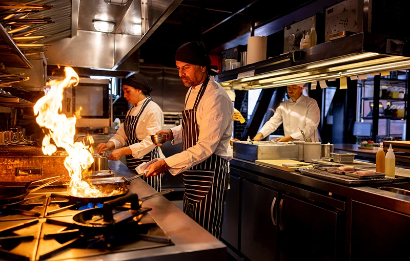 Chef cooking with an open flame in a commercial kitchen